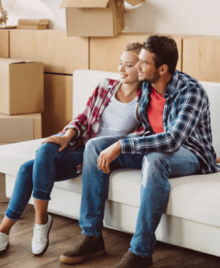 Couple sitting on their couch in front of packed moving boxes