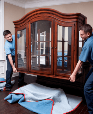 Movers moving a display cabinet inside a residential home