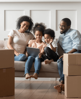 Family researching movers on an iPad near packed moving boxes